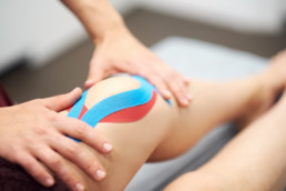 Kinesio-Tapes werden auf das Knie aufgeklebt