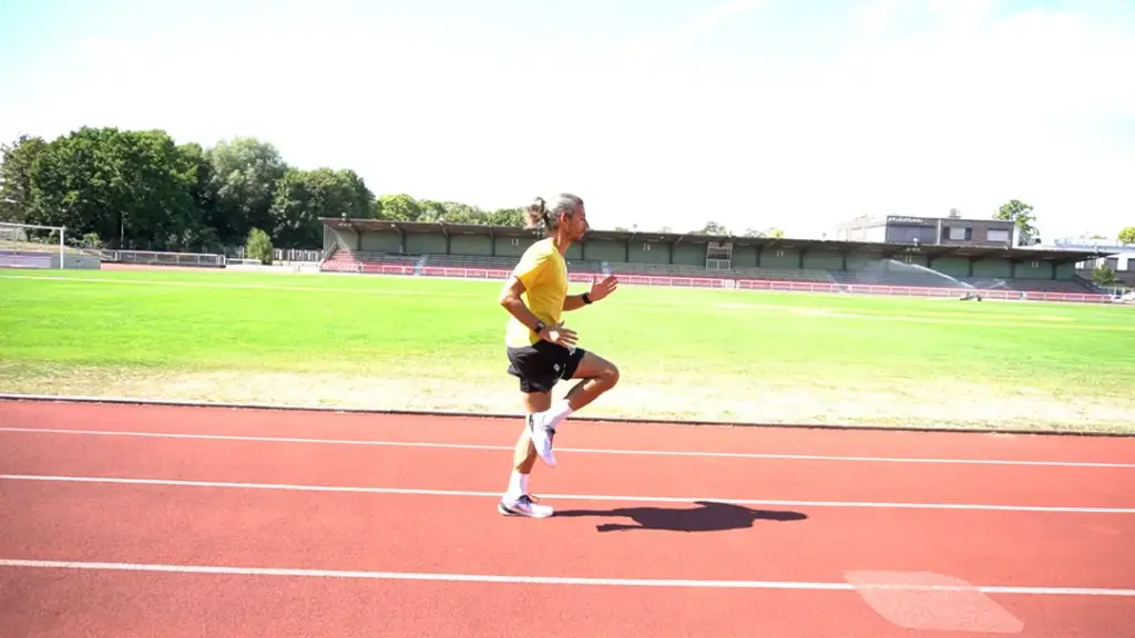 Läufer führt Skippings auf der Laufbahn durch – das rechte Knie wird gerade angehoben