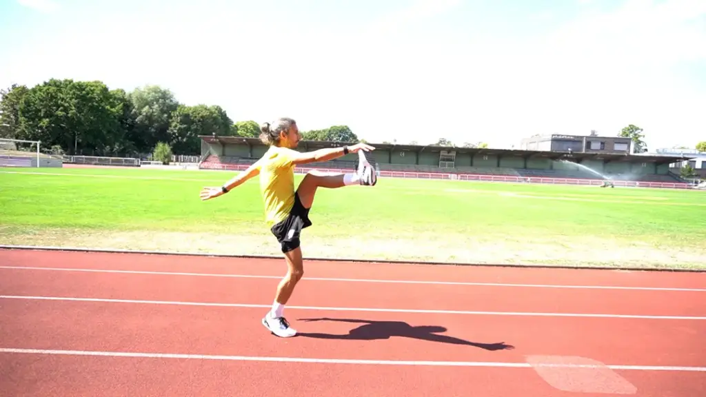 Läufer führt den Soldatenschritt auf der Laufbahn mit dem linken Bein durch